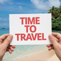 Hands hold card reading Time to Travel against a serene beach backdrop For Social Media Post Size photo