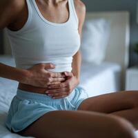 Woman in tank top rests hands on abdomen, creating calm, introspective moment For Social Media Post Size photo