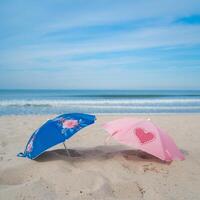 Two small umbrellas on sand, calm sea, and blue sky with gentle waves For Social Media Post Size photo