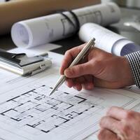 Hand holding silver pen over blueprint, capturing architectural precision and design focus For Social Media Post Size photo