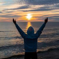 Silhouetted figure raises arms against sunset, conveying freedom and triumph For Social Media Post Size photo