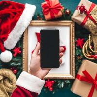 Hand holds smartphone with festive items around, capturing holiday shopping atmosphere For Social Media Post Size photo