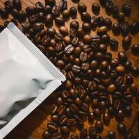 White packet on wooden surface, scattered coffee beans add texture and warmth For Social Media Post Size photo