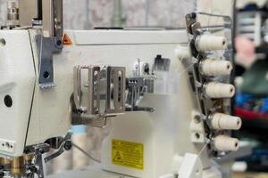 Sewing machine in a workshop with spools and tools visible photo