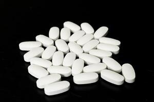 White tablets arranged on a black surface for identification purposes photo