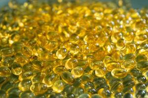 Golden gel capsules arranged closely on a flat surface photo