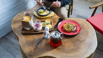 Enjoying a hearty brunch with eggs, dessert, and coffee on a wooden table photo