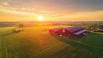 Aerial view of a large red barn surrounded by green fields during sunset photo
