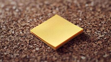 Square piece of shiny gold foil resting on textured brown surface photo