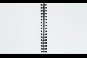 close up of two blank pages of sketch book with spiral bound against black photo