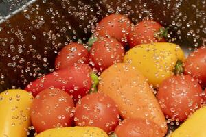 Fresh vegetables washed under running water in a kitchen sink photo