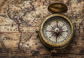 A vintage brass compass rests on an antique world map, suggesting themes of exploration, travel, navigation, and discovery photo