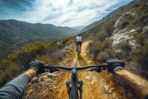 First person view of two mountain bikers descending a dusty trail in a mountainous region photo