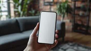 A hand holds a smartphone with a blank white screen. The background shows a blurred photo