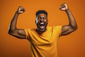 A dark skinned man with muscular arms raises his fists in triumph against an orange background photo