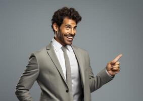 A smiling, happy businessman in a gray suit points to the side, conveying excitement and success. photo