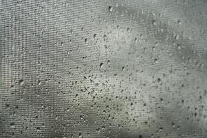 Rain droplets on a window screen during a cloudy day photo