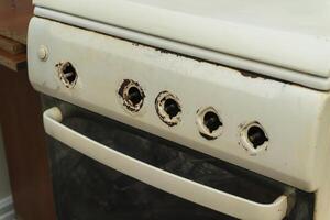 Old and worn kitchen oven with exposed knobs in need of repair photo
