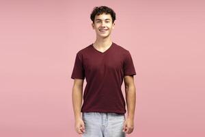 Smiling, attractive teen boy with braces wearing red t shirt, posing isolated on pink background photo