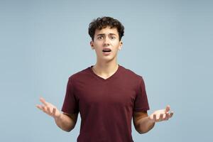 Excited, upset teen boy with open mouth looking at camera, standing isolated on blue background photo