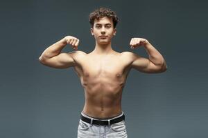 Handsome, attractive, young athlete with bare, muscles torso showing hands with biceps photo