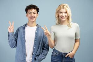 Portrait of happy, smiling boy and girl showing peace, victory symbol, looking at camera photo