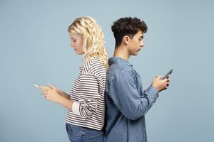 Portrait of attractive friends, holding mobile phone, standing back to back, using mobile app photo