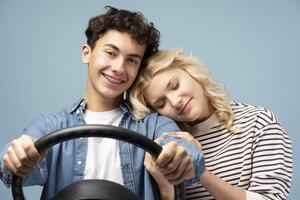 Smiling boy and girl with closed eyes, boyfriend holding helm, posing isolated on blue background photo