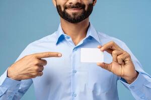Closeup portrait of smiling businessman holding empty white business card, pointing finger on mockup photo