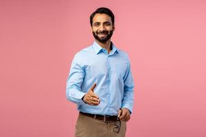 Portrait of smiling, handsome bearded Indian man taking handshake, looking at camera photo