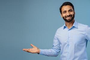 Portrait of smiling, positive, middle aged India man, businessman showing on copy space with hand photo