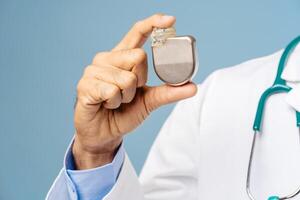 Portrait of professional doctor, cardiologist holding pacemaker selective focus on hands, closeup photo