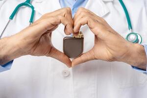 Professional doctor holding pacemaker, selective focus on hands, closeup. Cardiology concept photo
