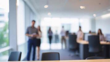 Blurry office setting with a wooden desk in the foreground and people working in the background. photo