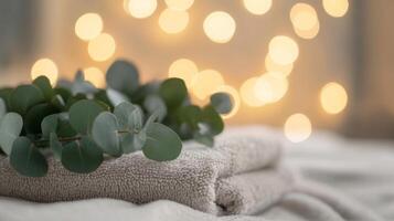 Soft towels are neatly stacked, adorned with fresh eucalyptus leaves, contributing to a serene and eco-conscious beauty space. Subtle lights twinkle in the background, enhancing the ambiance. photo