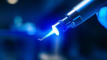 A dental professional prepares to utilize advanced laser technology in a clinical setting. The tool emits a focused blue light, emphasizing precision and innovation in dental treatments. photo