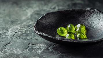 Five striking green gemstones are arranged on a textured black dish, showcasing their glossy surfaces and natural shapes. The dark backdrop enhances their vivid hues and intricate details. photo