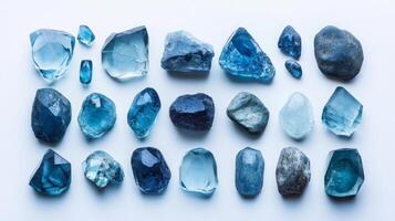 A collection of blue gemstones displayed in a variety of shapes and sizes showcases their unique qualities. Each stone exhibits a striking hue, reflecting light beautifully in a serene arrangement. photo