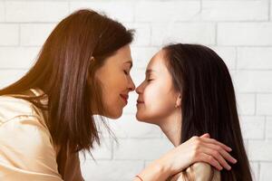 Loving mother and her carefree daughter touching noses, expressing their affection at home. Panorama photo