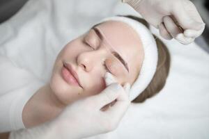 Two woman are engaged in a pampering beauty session at a salon, focusing on a permanent makeup procedure. One woman is applying makeup while the other relaxes during the treatment. photo