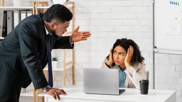 Displeased male boss scolding upset female employee for mistake in company project or missed deadline at modern office. Workplace challenges and difficulties concept photo
