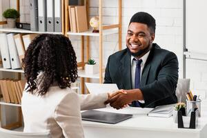 Happy personnel manager and young job applicant shaking hands at modern company office photo
