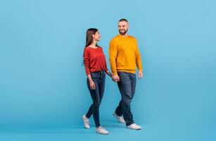 A married couple walks hand in hand, smiling at each other with love. The scene captures their connection and happiness in matching casual attire, creating a vibrant atmosphere. photo