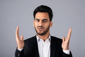 A Middle Eastern businessman in a suit conveys surprise with his hands raised. He is in a studio setting, focusing on entrepreneurial concepts and corporate strategies. photo