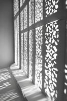 Intricate shadows cast by sunlight through patterned lattice windows photo