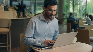 Arabian Indian man typing laptop keyboard concentrated business guy male businessman at cafe table online work computer browsing internet write tasks thinking freelancer manager employee distant study photo