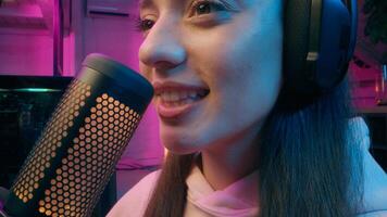 Joyful Caucasian girl host woman influencer blogger female vlogger hold microphone stream at home neon addict streamer presenter talk radio broadcast play online game computer cyber sport blog photo