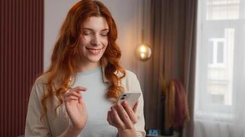 Happy joyful Caucasian woman looking mobile phone device swipe screen at home. Satisfied positive emotion female lady smile enjoying online scrolling feed web girl chatting playing virtual game photo