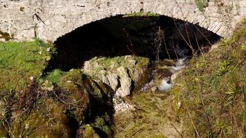 An ancient rock bridge across a small stream video
