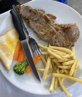 Delicious grilled steak dinner with fries and vegetables restaurant food presentation indoor setting culinary delight photo